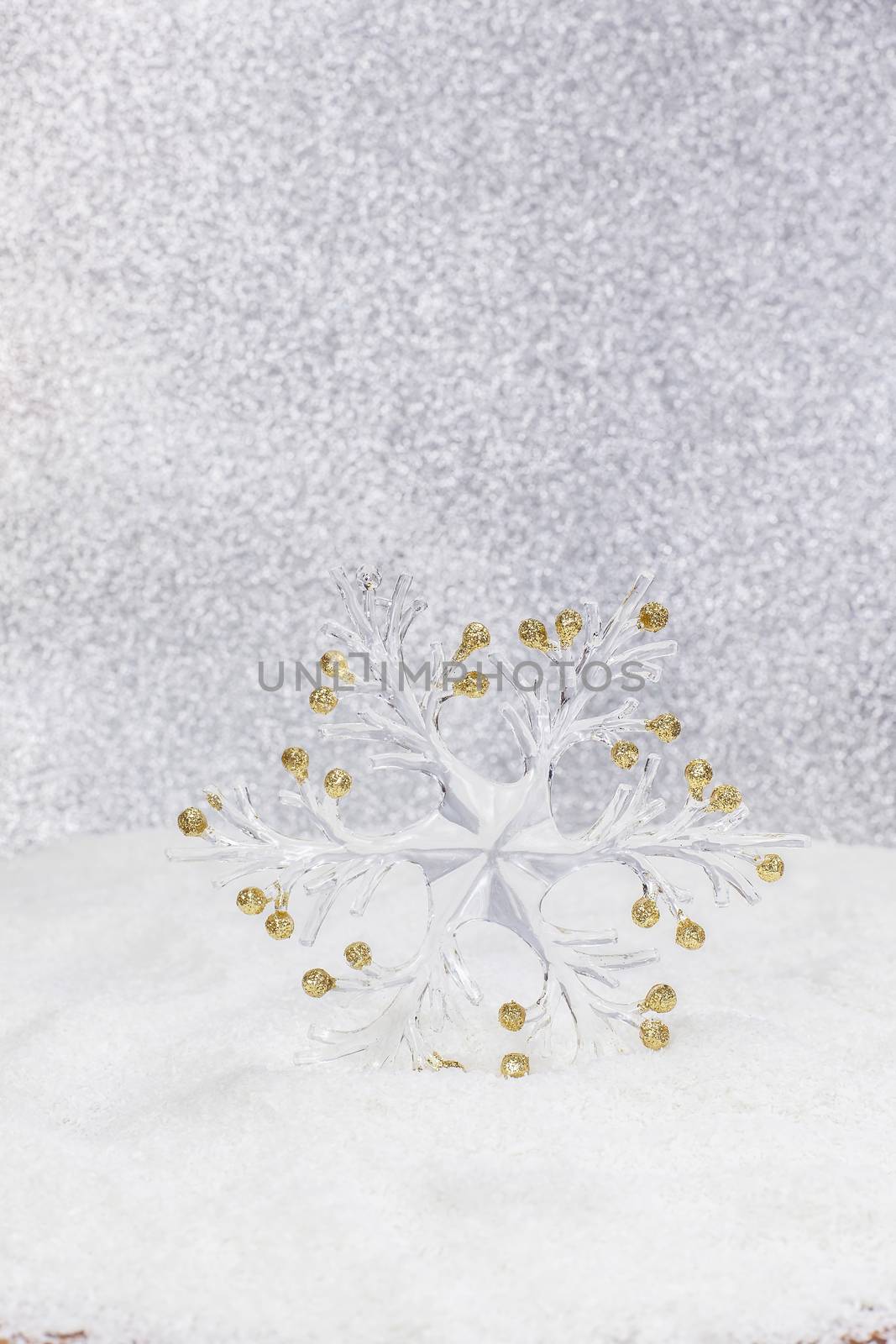 Snowflake on glitter background with bokeh effect and place for text. High key with shallow depth of field