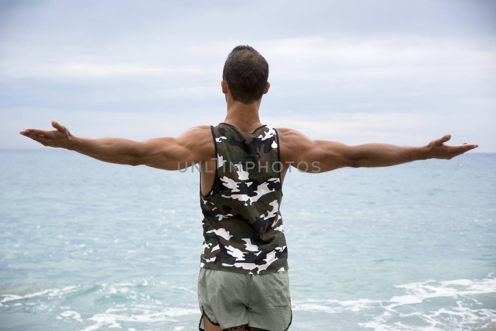 Muscular young man on the beach seen from the back by artofphoto