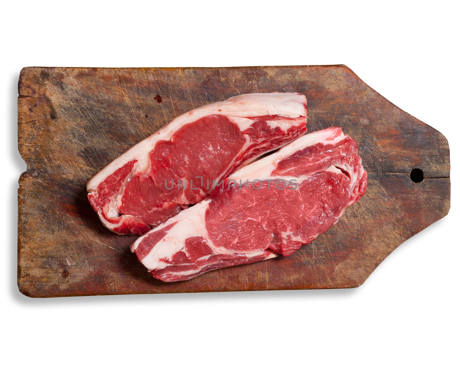 Argentinean "bife de chorizo" raw meat on wooden table. Clipping path excludes shadow.