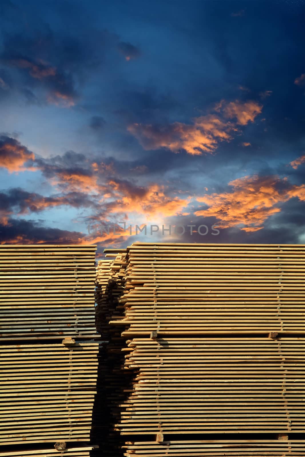 Stacked lumber with a nice sunset behind.
