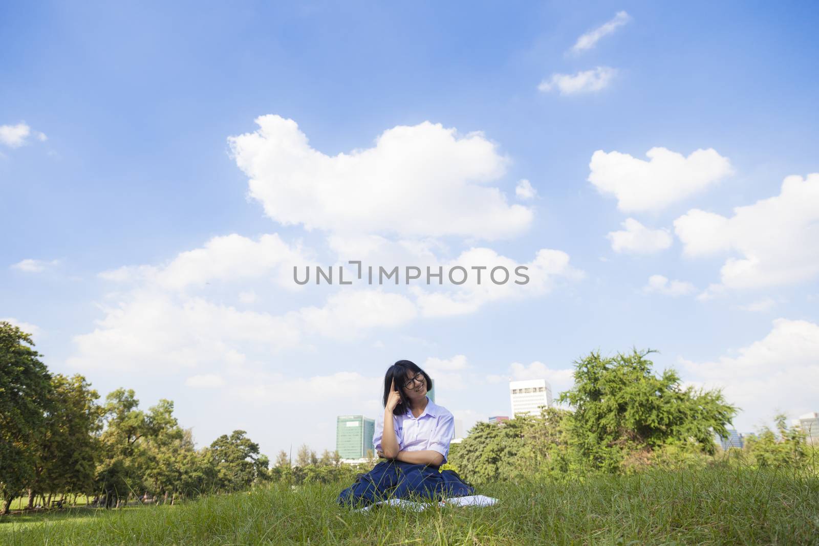 Student homework sitting on the lawn. In the Park on a clear day. The sky is clearing up.