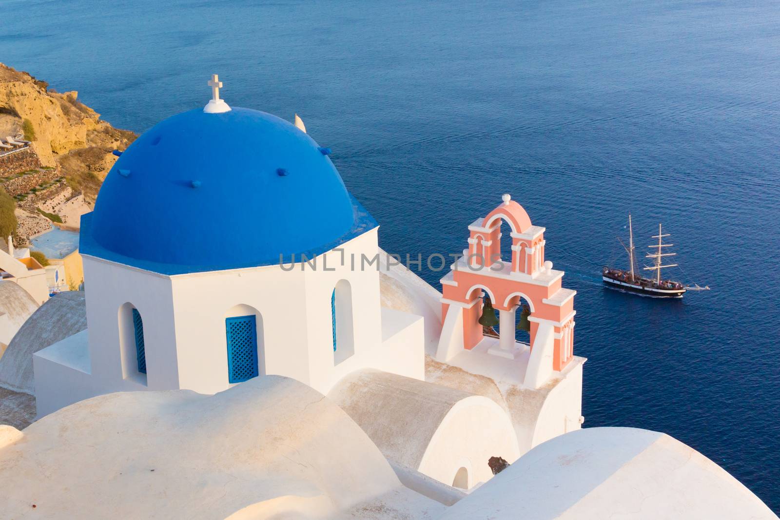 World famous traditional whitewashed chuches and houses of Oia village on Santorini island, Greece. Sunset light.