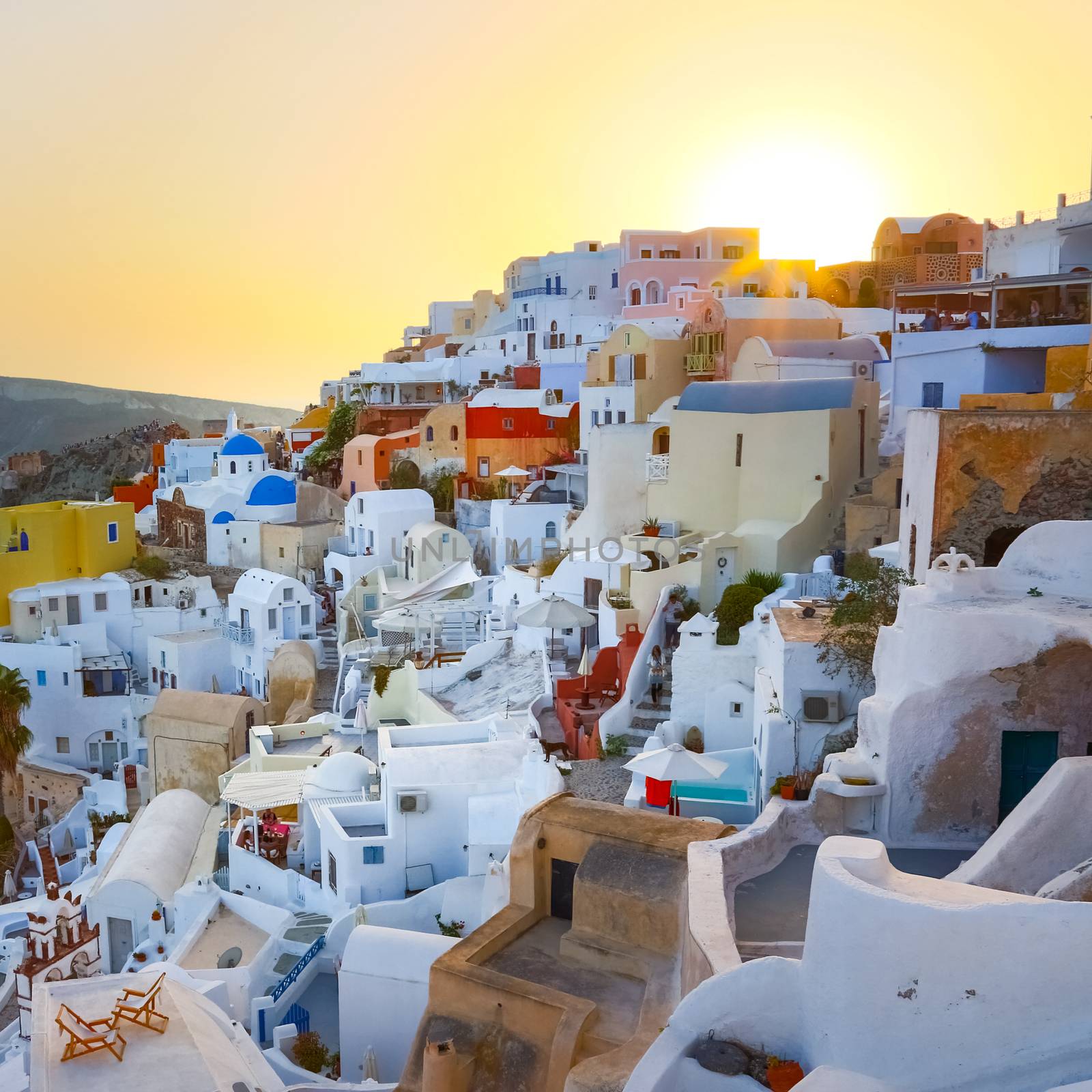 World famous traditional whitewashed chuches and houses of Oia village on Santorini island, Greece. Sunset.