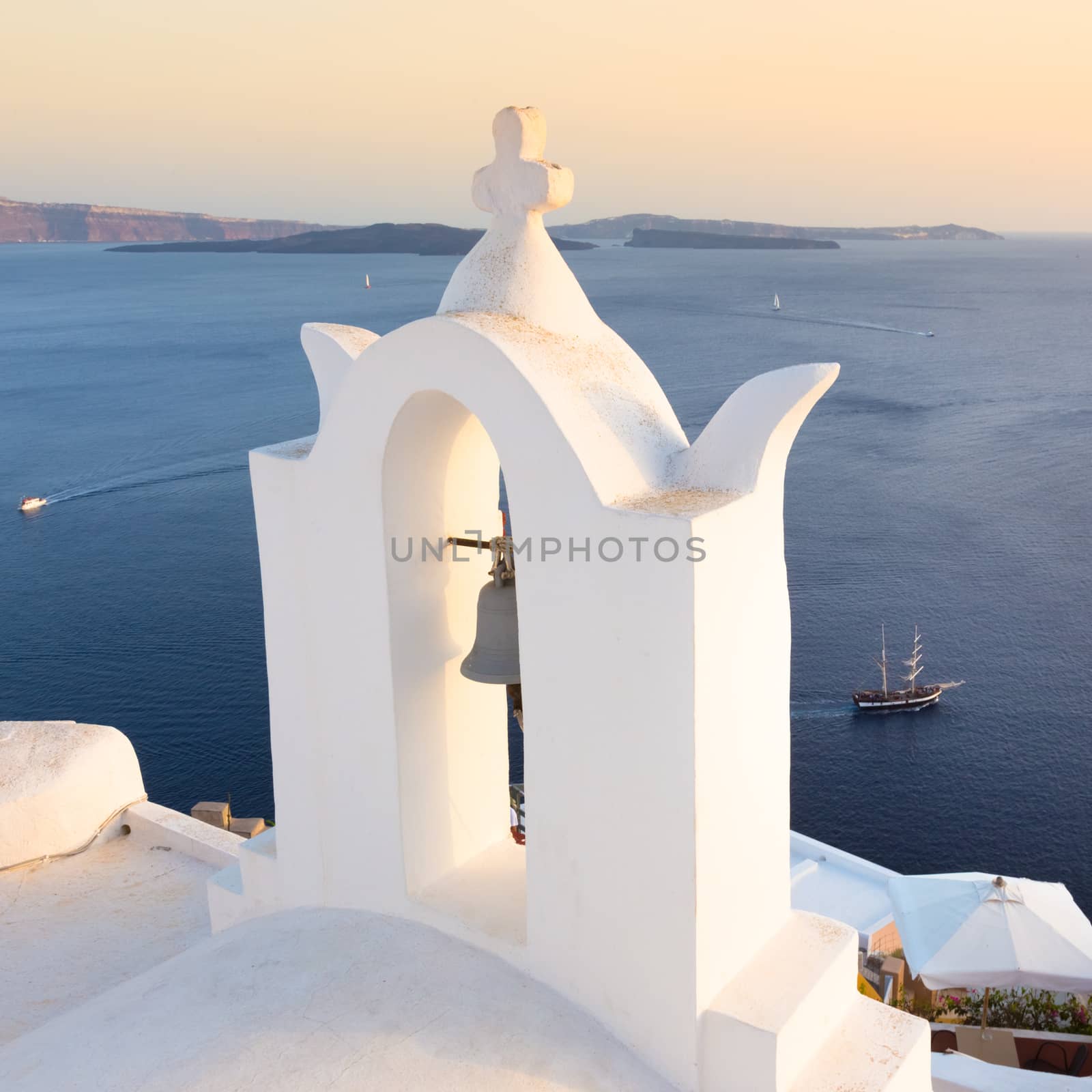 World famous traditional whitewashed chuche of Oia village on Santorini island, Greece. Sunset light.