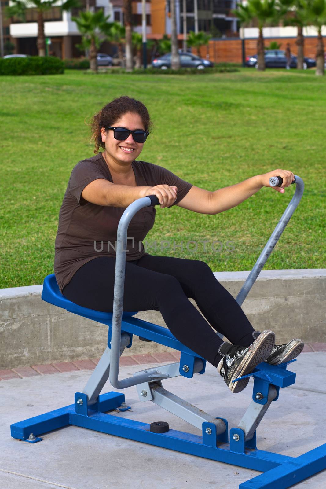 Young latina doing some exercise in a park on a leverage training equipment 