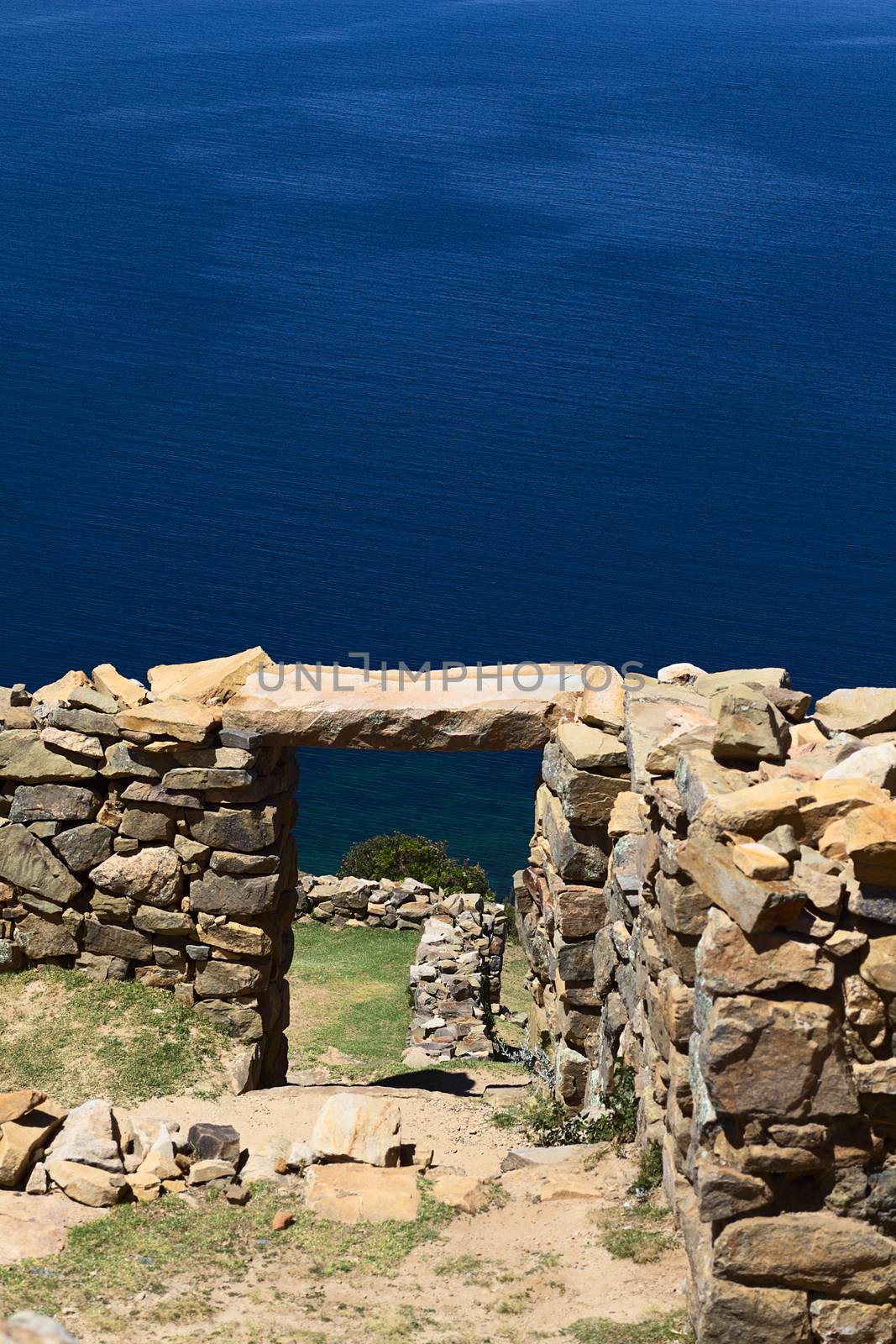 View through a door frame of the Chinkana archeological site of Tiwanaku (Tiahuanaco) origin on the Northwestern part of the Isla del Sol (Island of the Sun) in Lake Titicaca in Bolivia. Isla del Sol is a popular tourist destination and is reachable by boat from Copacabana, Bolivia. (Selective Focus, Focus on the door frame and beyond)