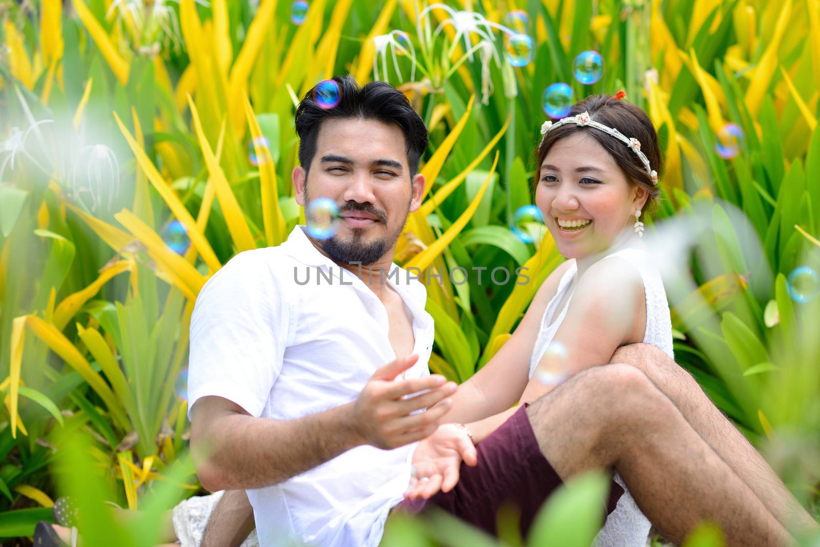 happy asian couple play together with bubble in garden