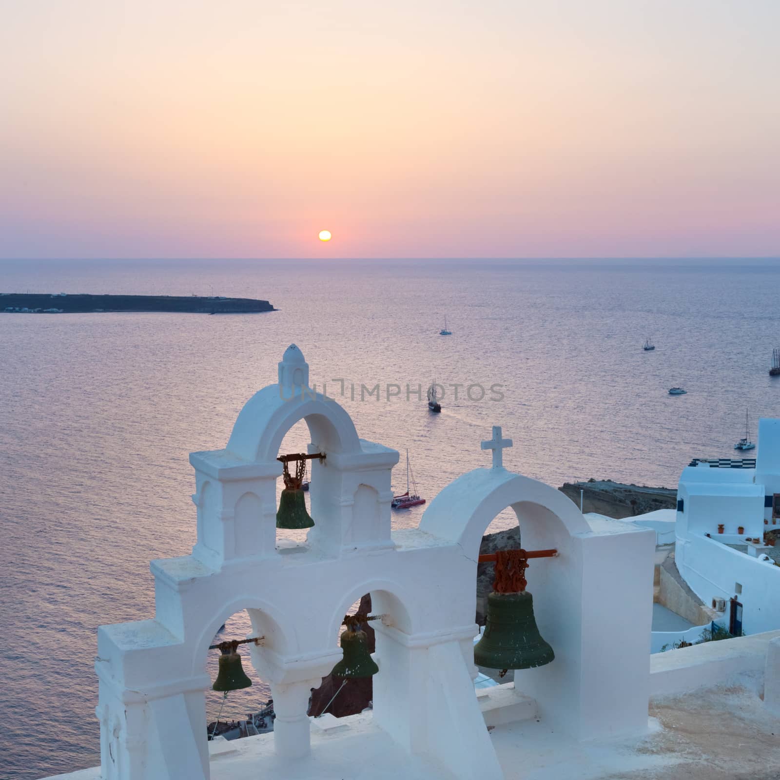 World famous traditional whitewashed chuche of Oia village on Santorini island, Greece. Sunset light.
