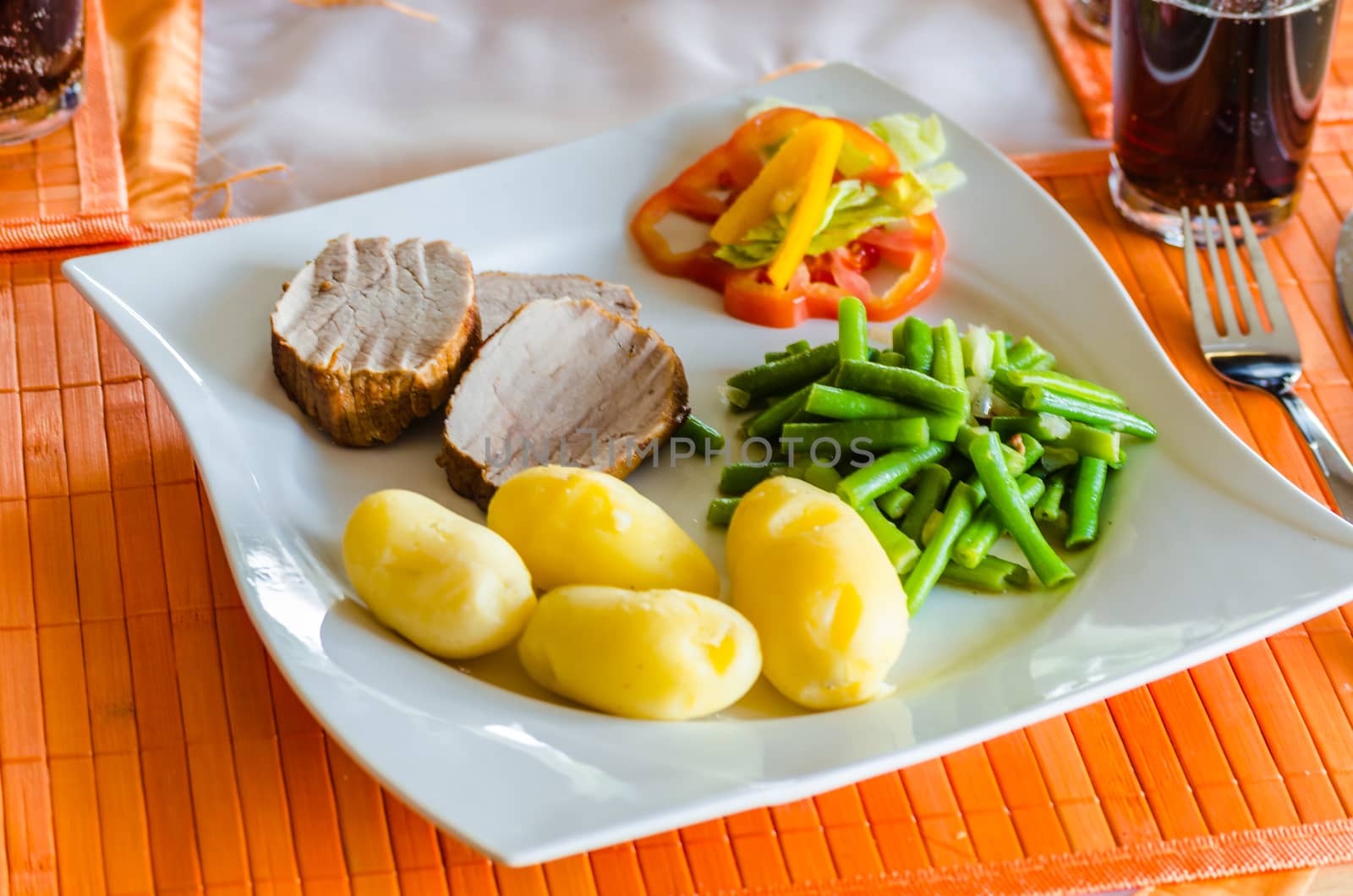 Fresh roast pork with potatoes on a white plate.