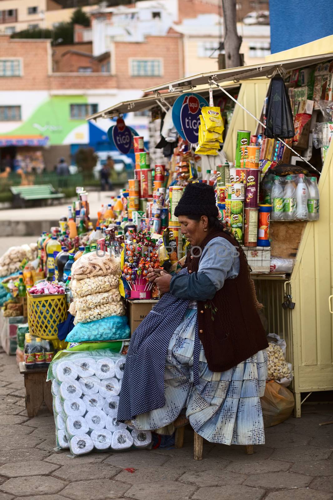 TIQUINA, BOLIVIA - OCTOBER 16, 2014: Unidentified woman sitting at a snack stand and doing crochet at the main square on October 16, 2014 in San Pedro de Tiquina, Bolivia