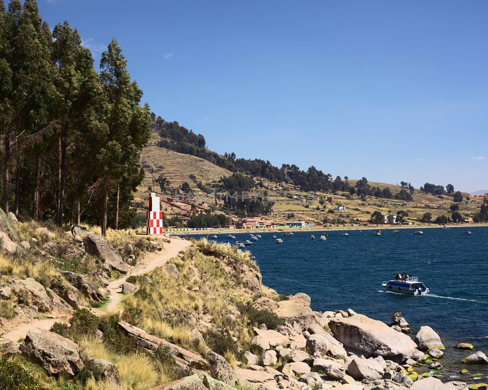 COPACABANA, BOLIVIA - OCTOBER 17, 2014: Beacon on the shore of Lake Titicaca at the small tourist town on October 17, 2014 in Copacabana, Bolivia. In the back a tour boat is entering the bay of Copacabana. 