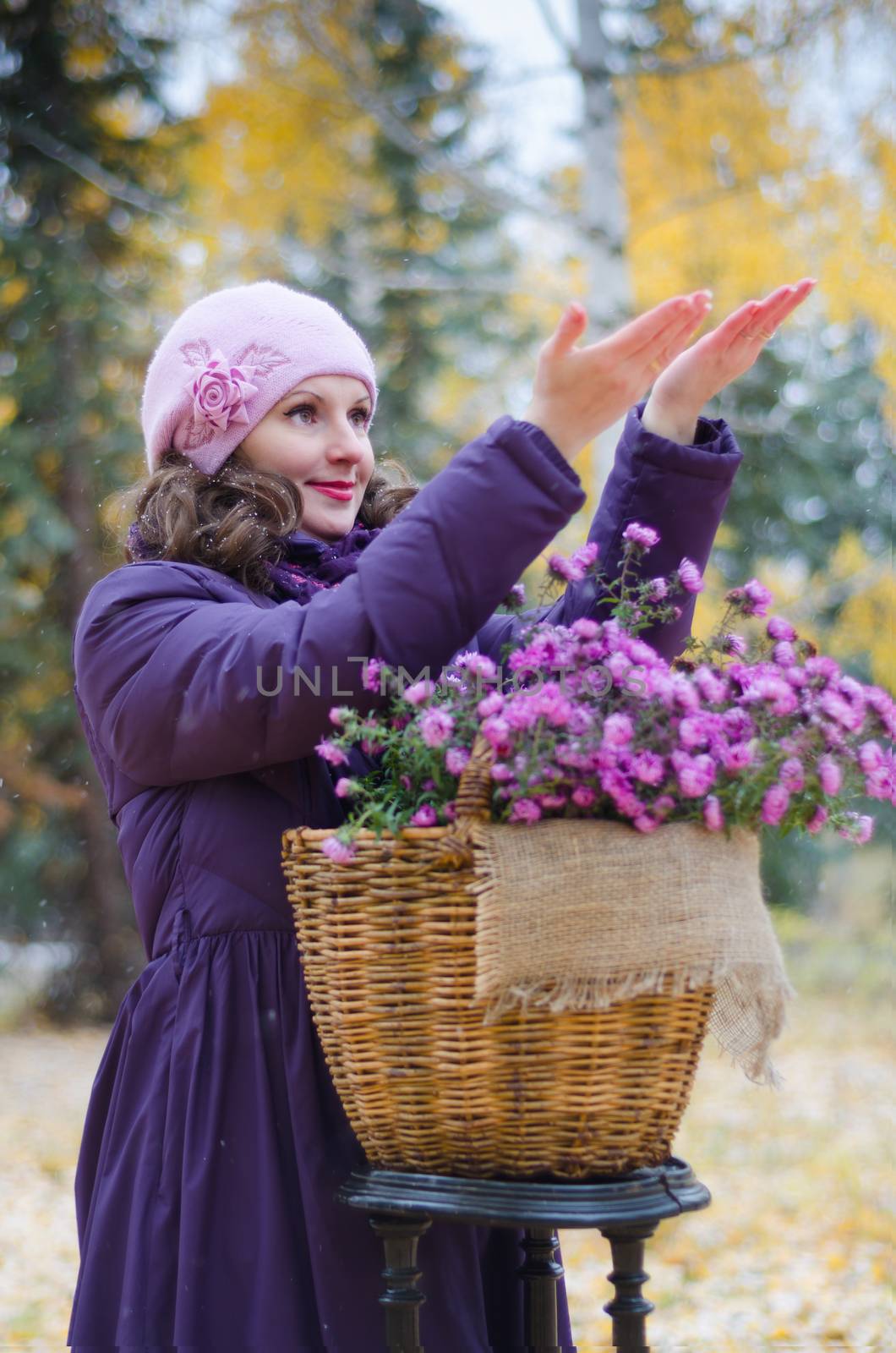 Beautiful girl in the Park, with a basket of flowers. She catches in the palm of the first snow, and rejoices.