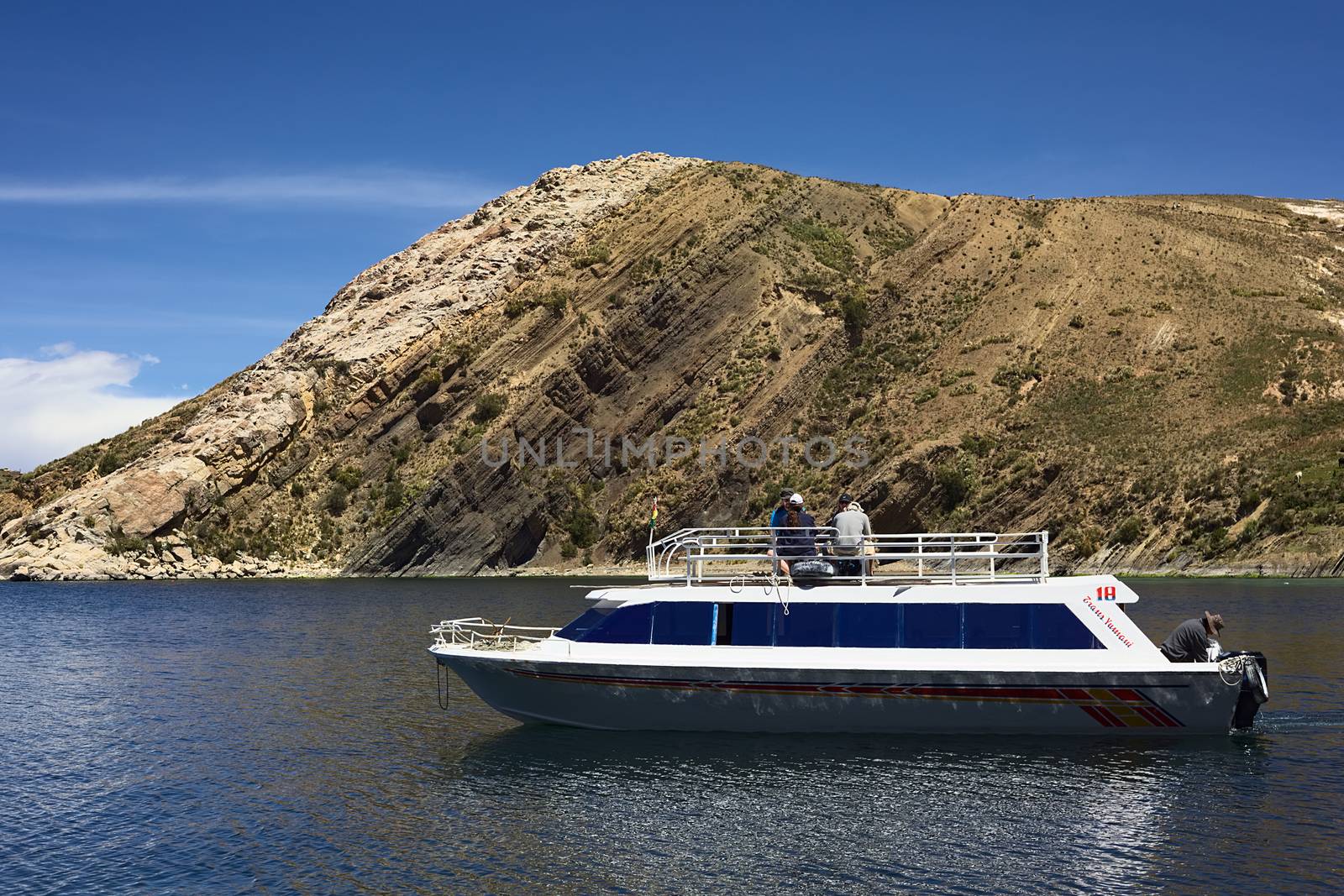 ISLA DEL SOL, BOLIVIA - NOVEMBER 6, 2014: Unidentified people sitting on the roof of a tour boat leaving the Isla del Sol (Island of the Sun) on November 6, 2014 at Isla del Sol, Bolivia. Isla del Sol is a popular tourist destination in Lake Titicaca.  