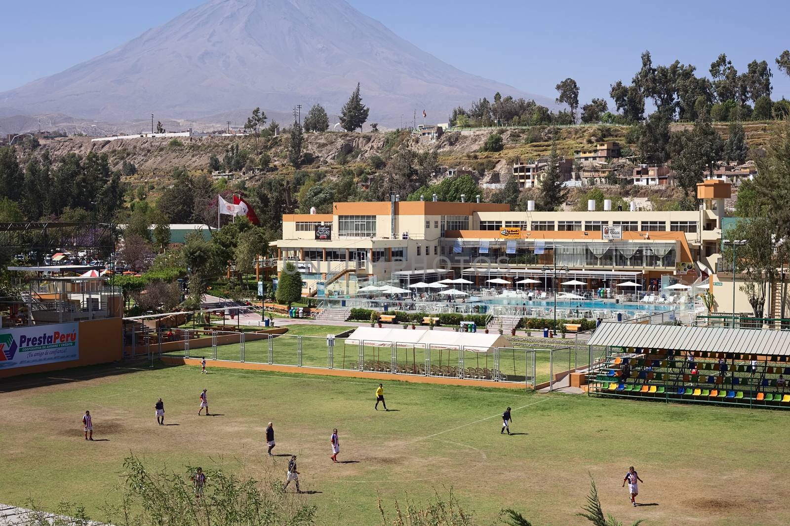 AREQUIPA, PERU - AUGUST 23, 2014: Unidentified men playing football on pitch at the Club Internacional Arequipa (International Country Club) on August 23, 2014 in Arequipa, Peru. In the back the volcano Misti is visible. 