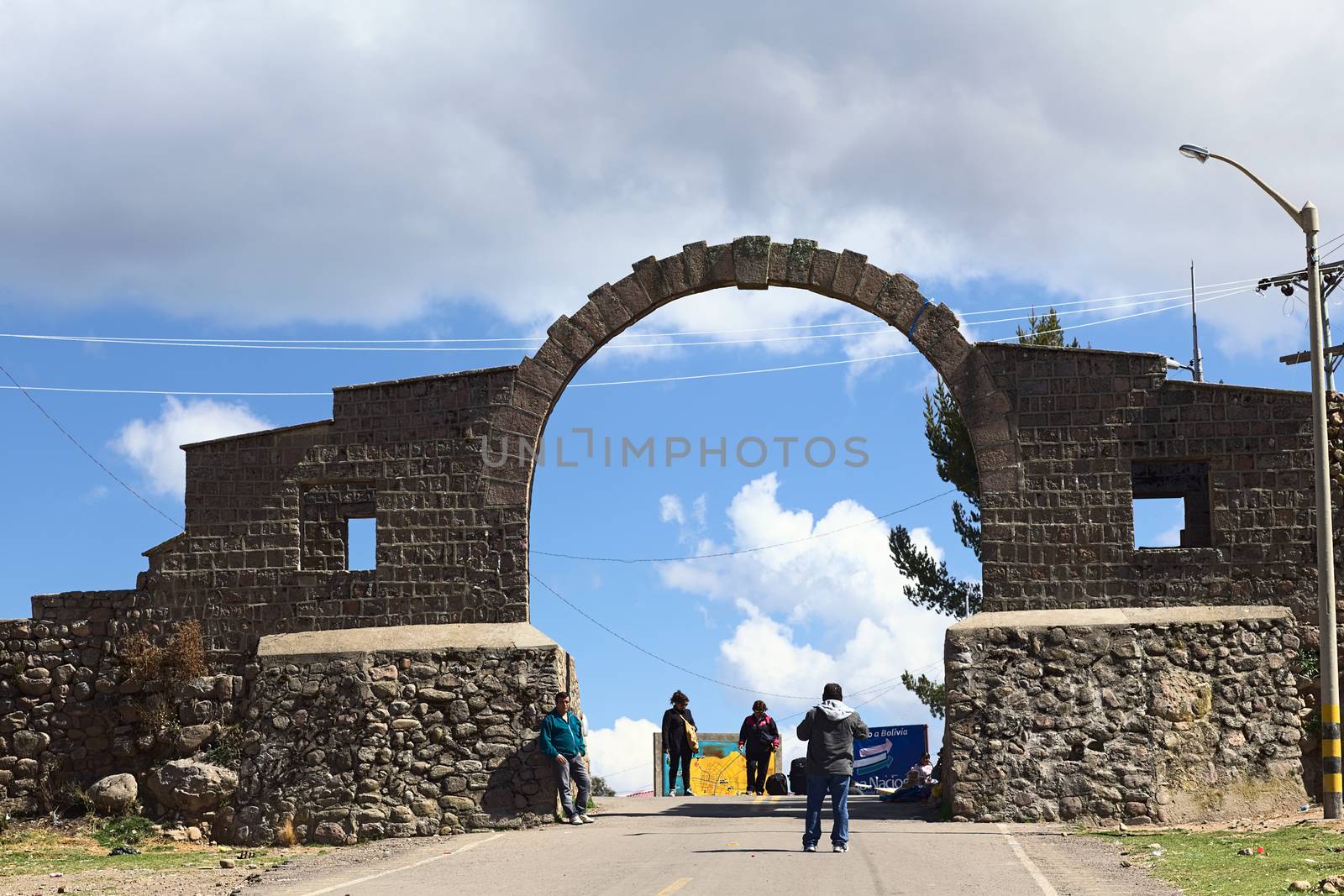 YUNGUYO, PERU - OCTOBER 10, 2014: Unidentified people standing at the arch on the border between Yunguyo (Peru) and Kasani (Bolivia) photographed from the Peruvian side on October 10, 2014 in Yunguyo, Peru