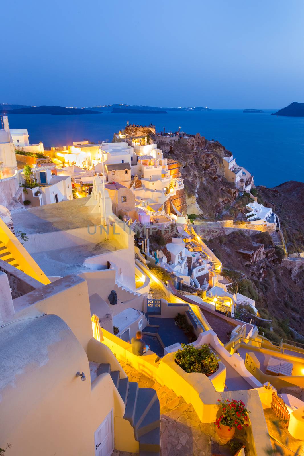 World famous traditional whitewashed chuches and houses of Oia village on Santorini island, Greece. Sunset.