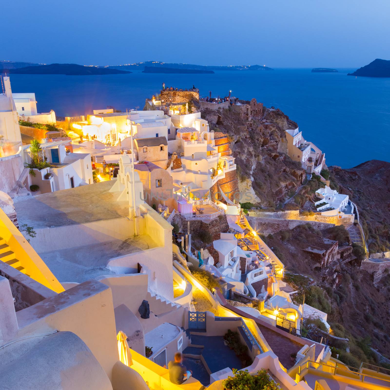 World famous traditional whitewashed chuches and houses of Oia village on Santorini island, Greece. Sunset.