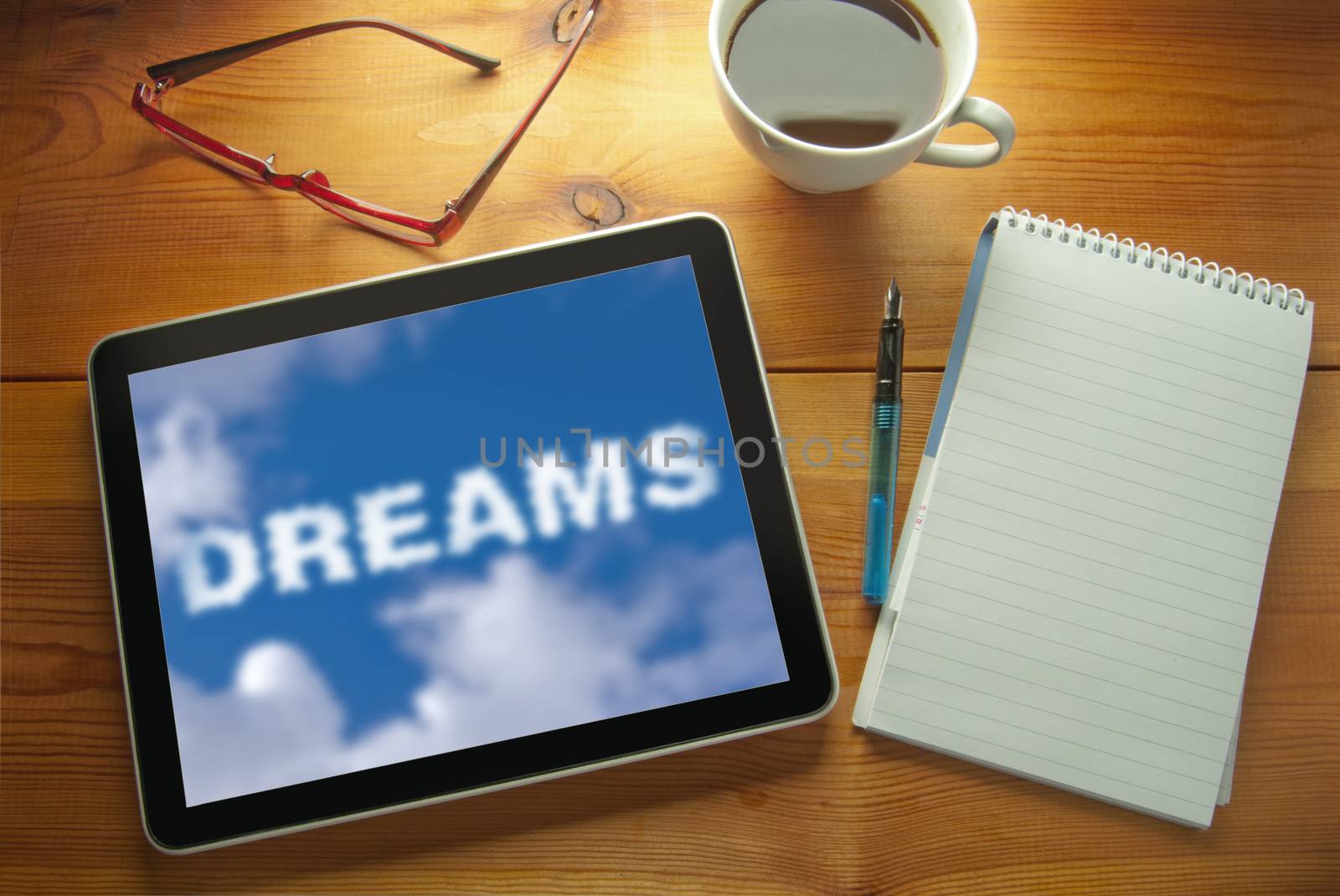 Computer tablet on a work desk with dreams cloud 
