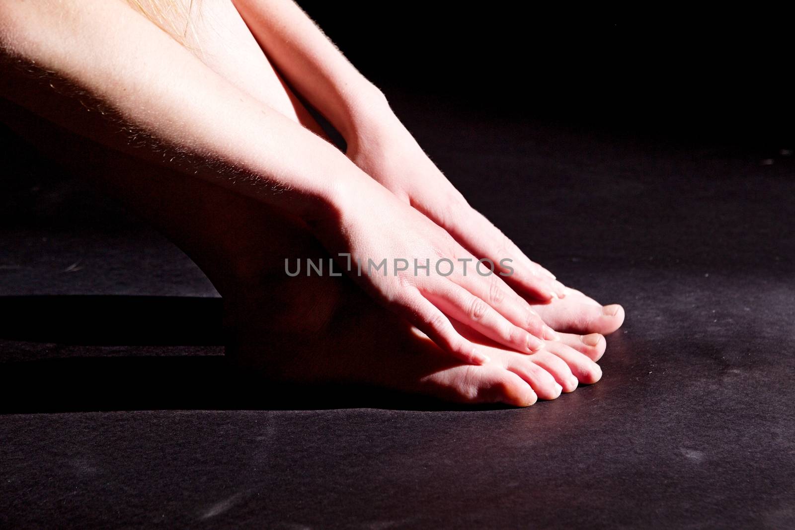 Photo shows a woman lighted and shadowed on the black background.