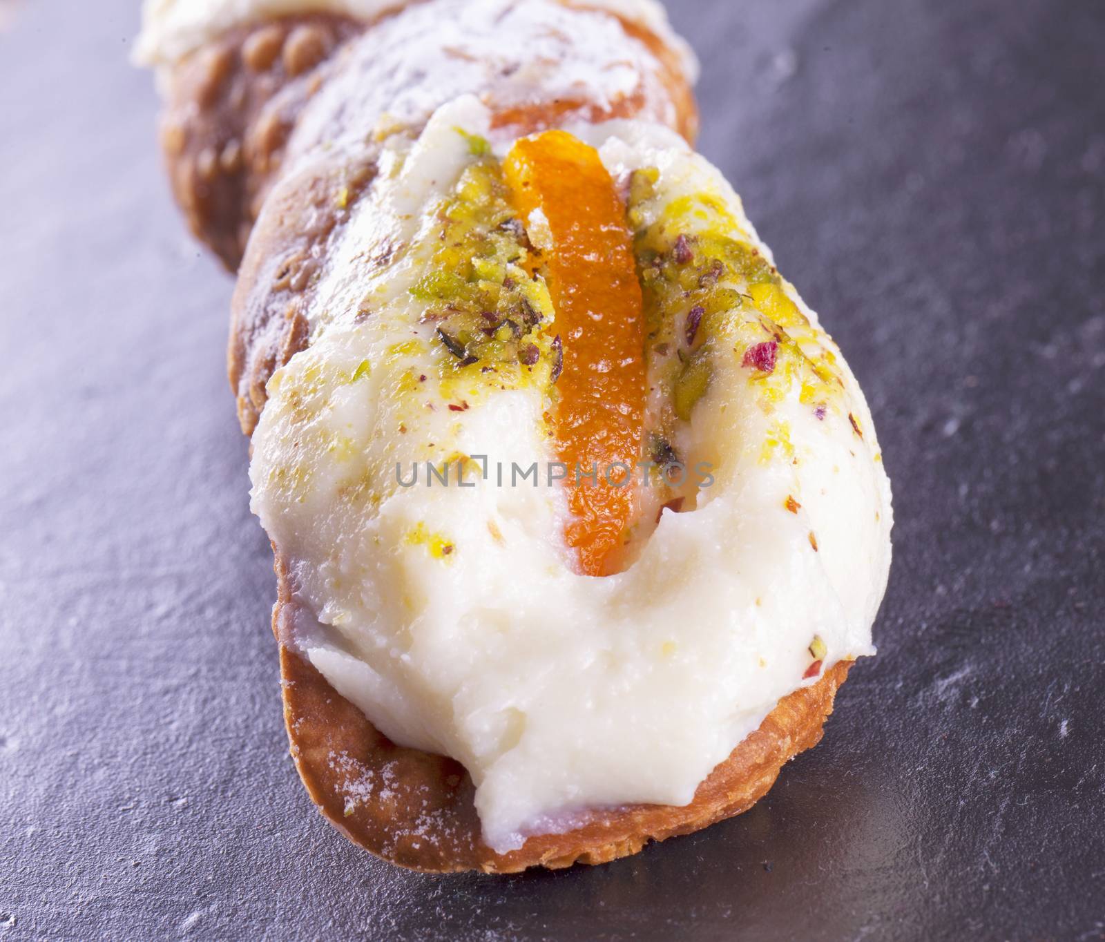 Typical sicilian cannolo, lying over black stone background