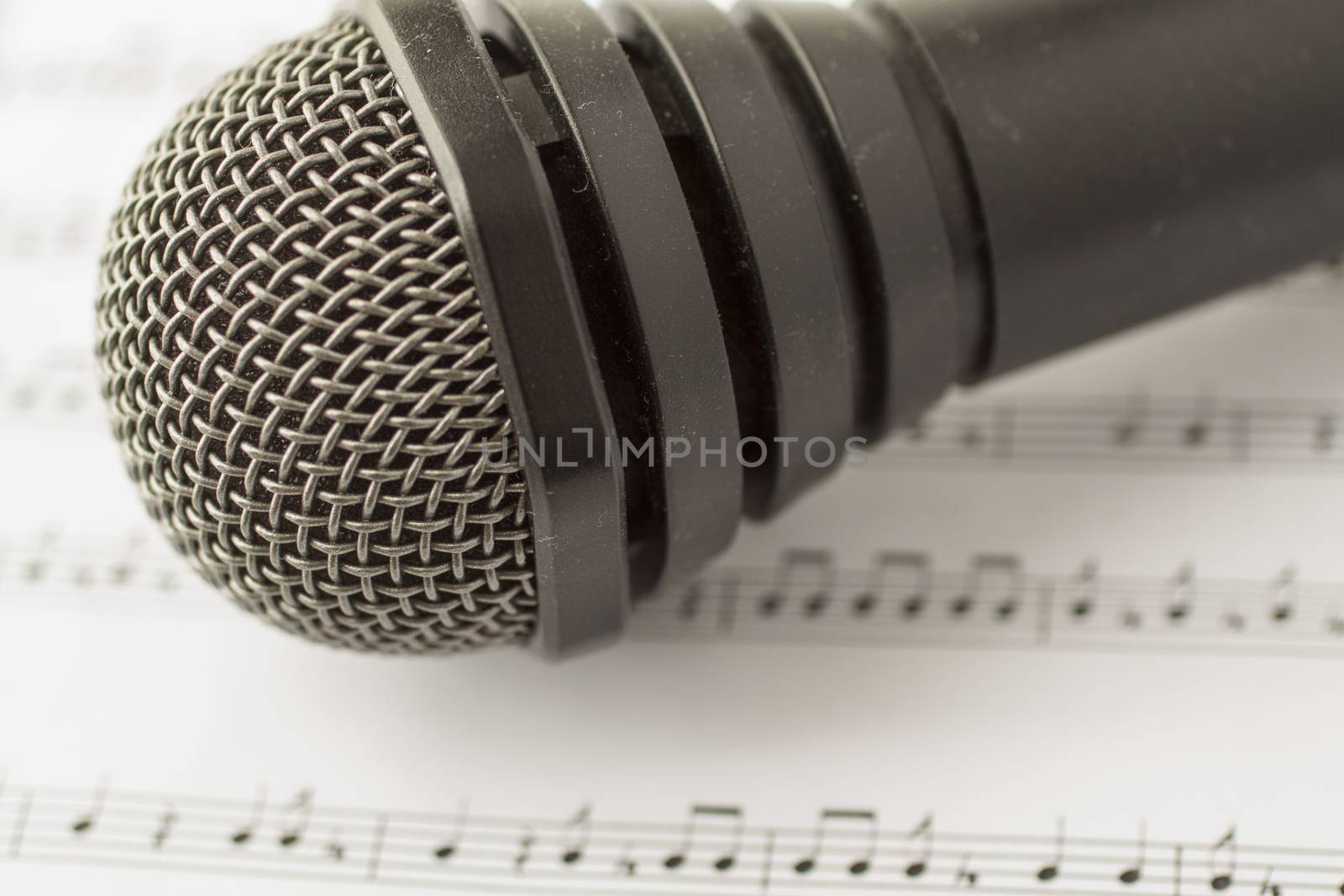 Black microphone over musical score, horizontal image