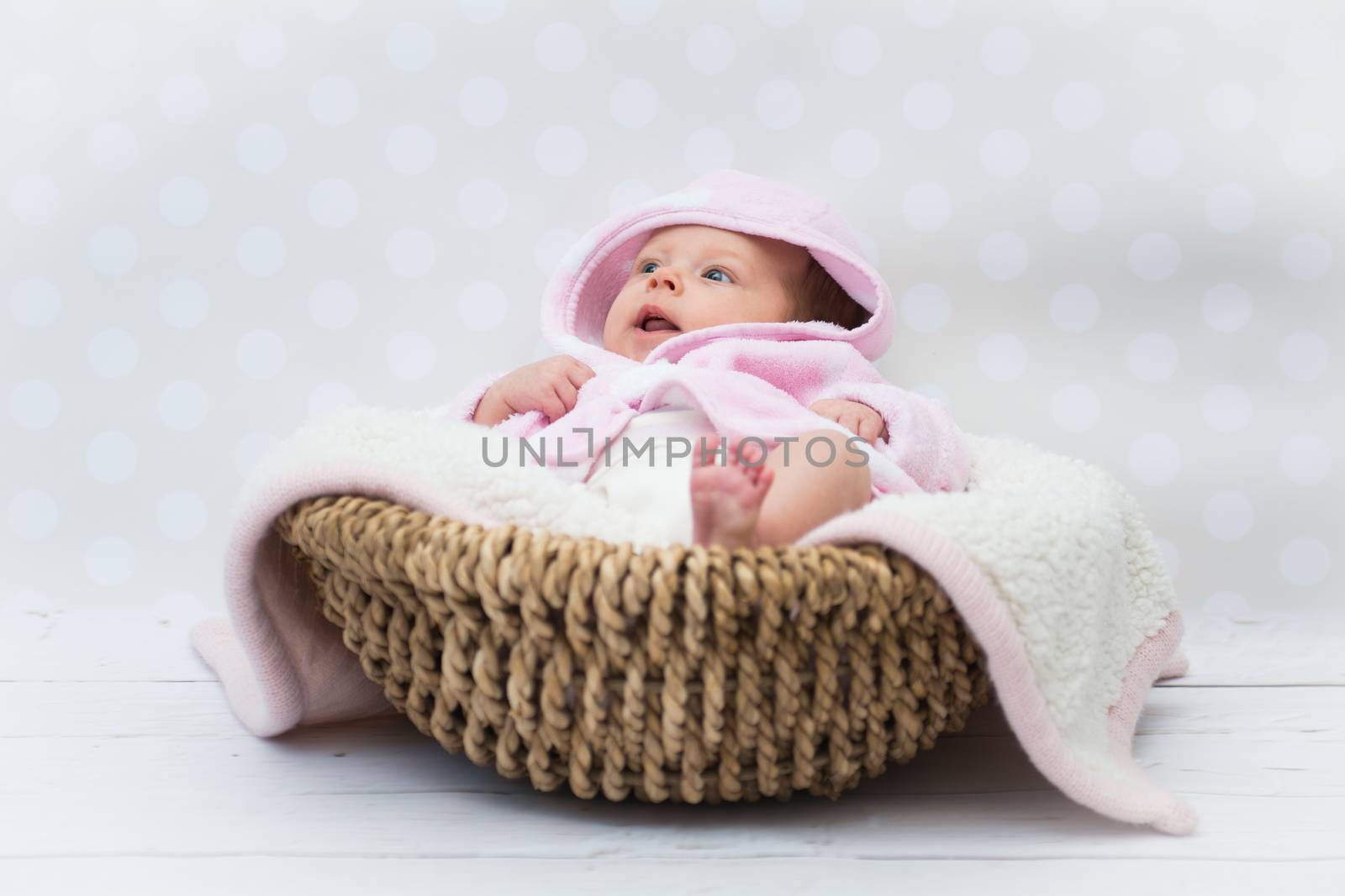 baby girl in a pink bathrobe sitting in a basket