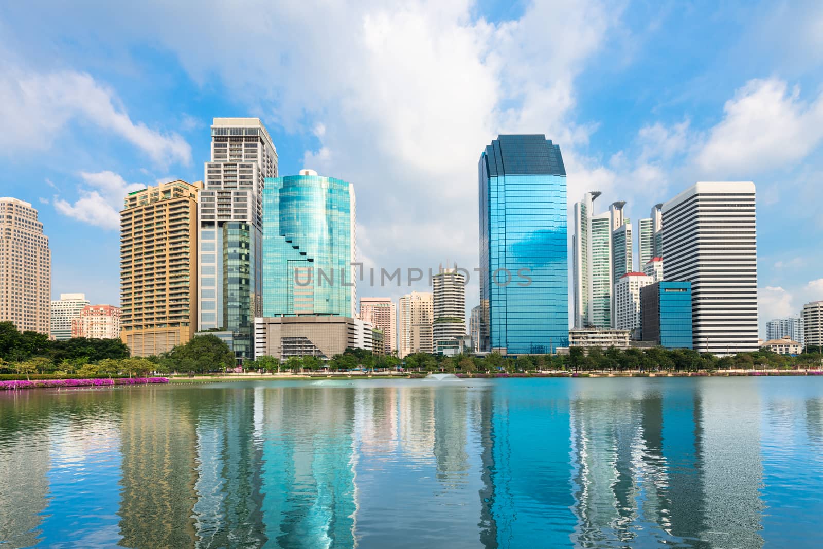 Modern city skyline with reflection in lake under blue sky by iryna_rasko
