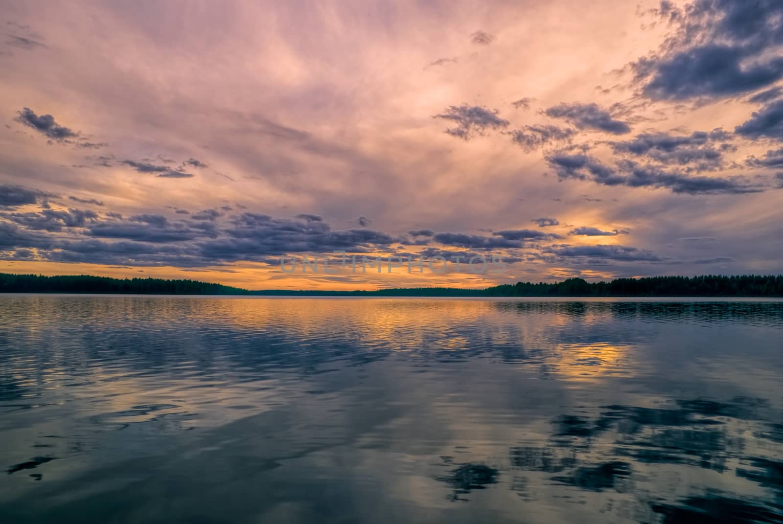 Breathtaking view of sunset behind windswept sky reflected in a lake