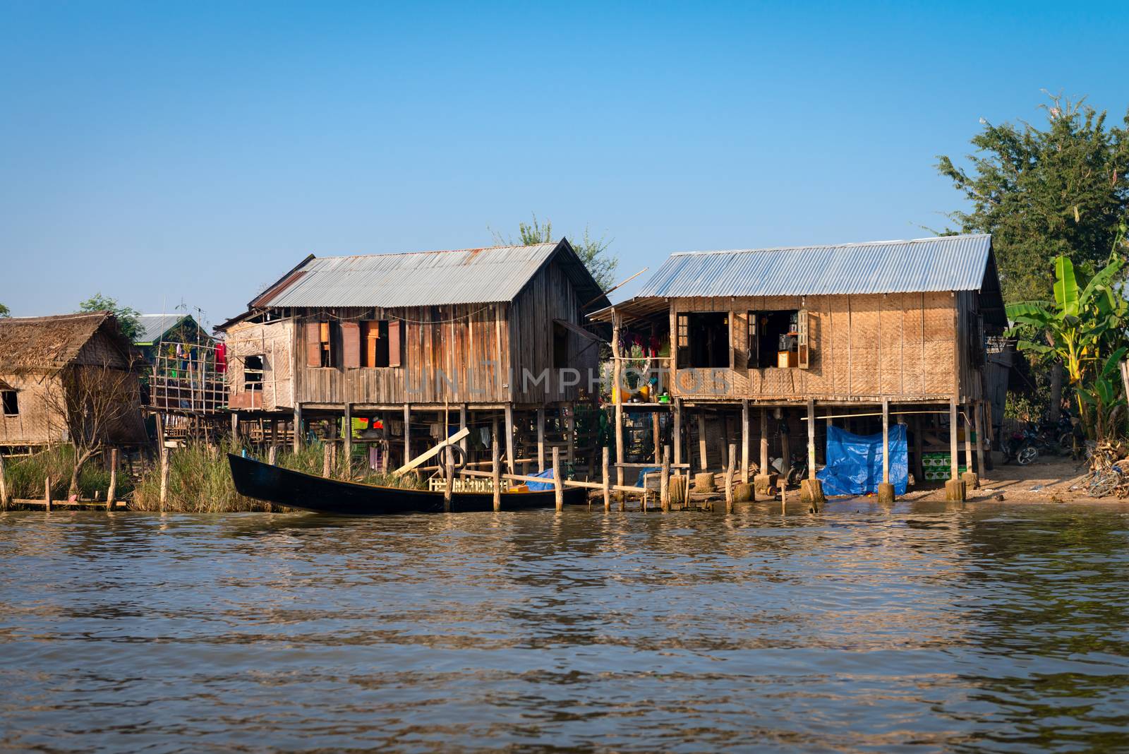 Traditional stilts wooden and bamboo houses and long boats of Intha people in water on Inle lake, Myanmar (Burma) 