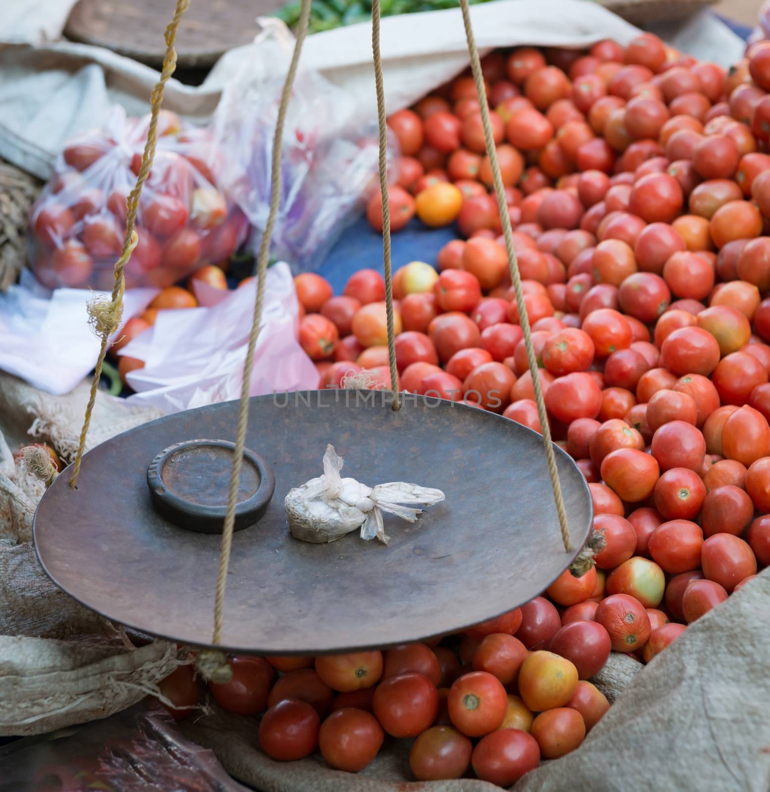 Metal scale pan of simple vintage balance with weight on traditional open market with tomato vegetables on background 
