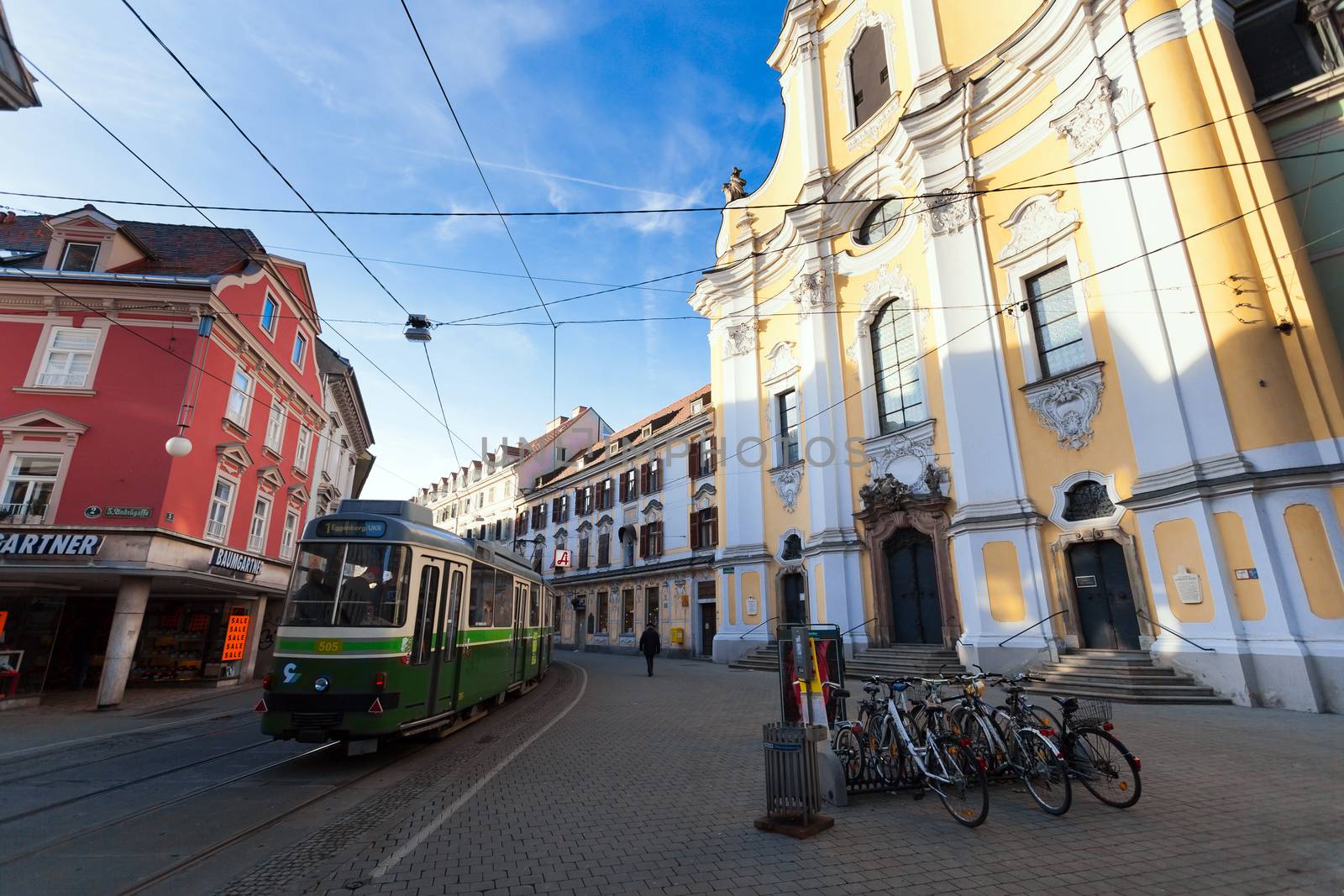 Graz, Austria - January 16, 2011: View of Annenstrasse street with typical green tram and Brotherhood Baroque Church in Graz, Austria