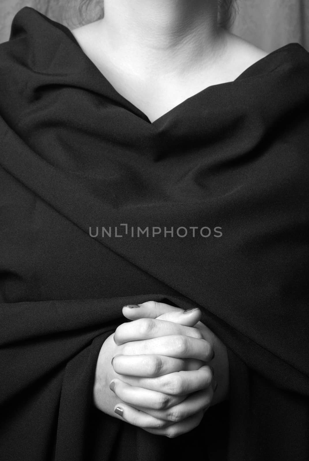 A black and white image of a womans hands clasped in prayer.