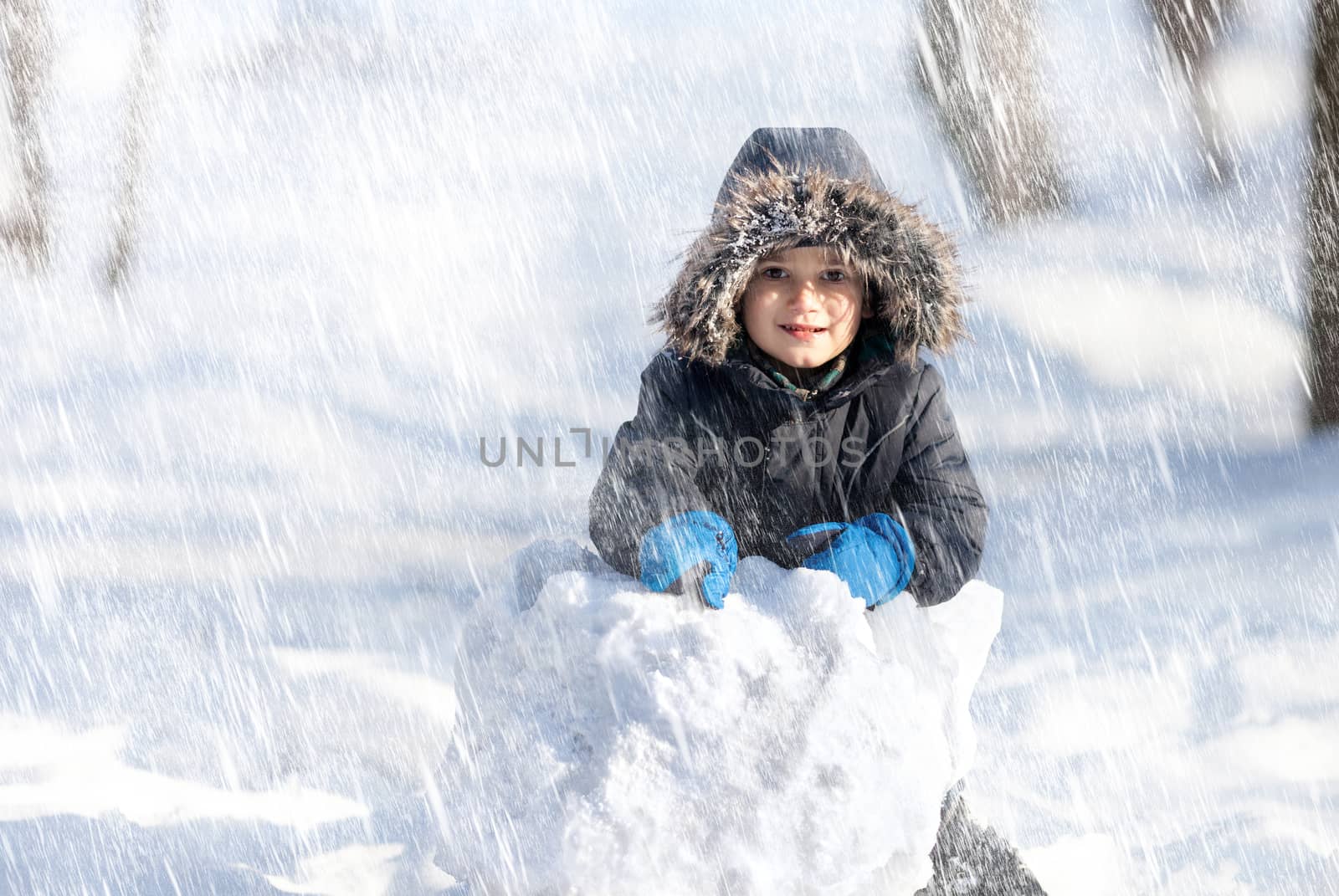 Snowfall. Cute boy playing with snow in the winter park 