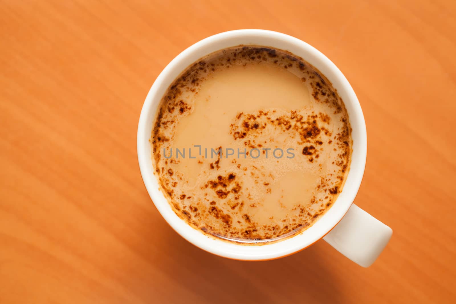 Coffee with milk in white mug on the kitchen counter from above