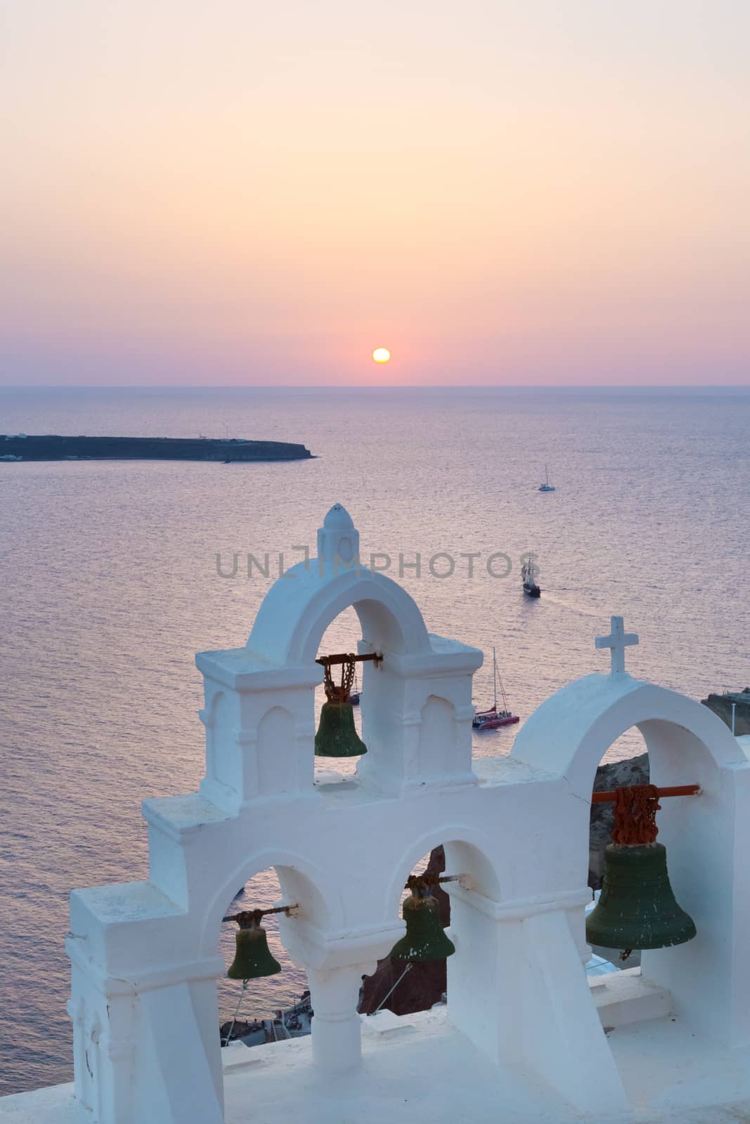 World famous traditional whitewashed chuche of Oia village on Santorini island, Greece. Sunset light.