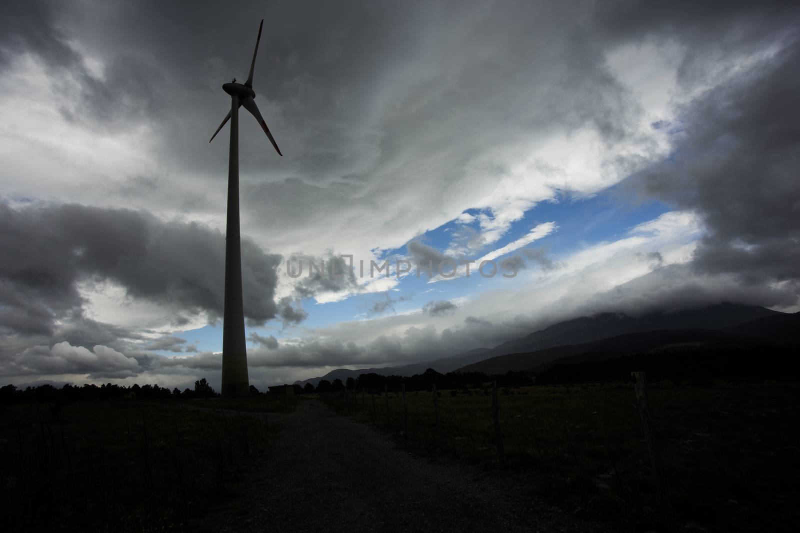 Wind turbine silhuette, with dark landscape background.