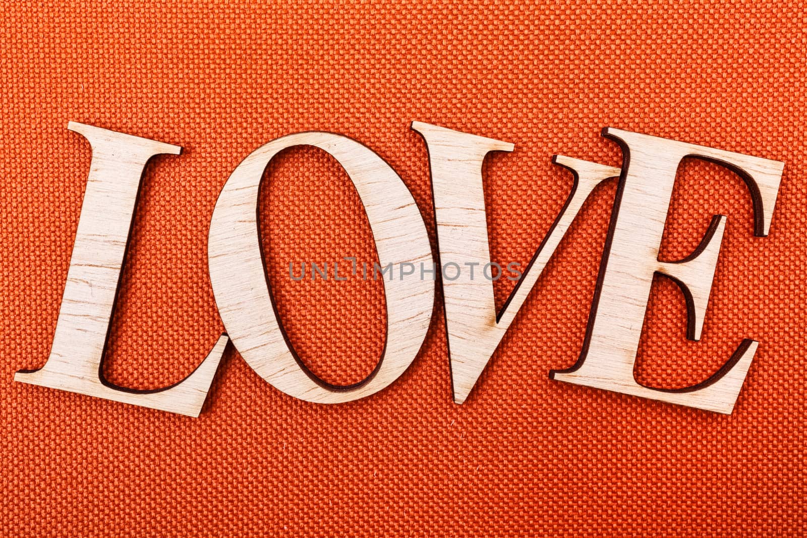 Wooden letters forming word LOVE written on orange background