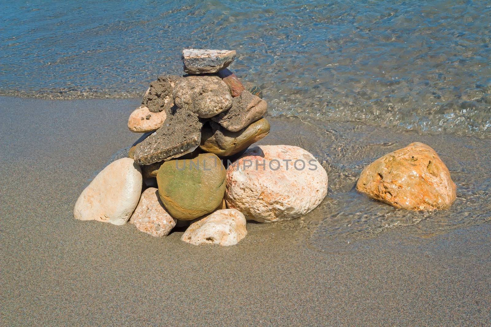 Small multi-colored sea stones on the beach, covered with transparent sea water.