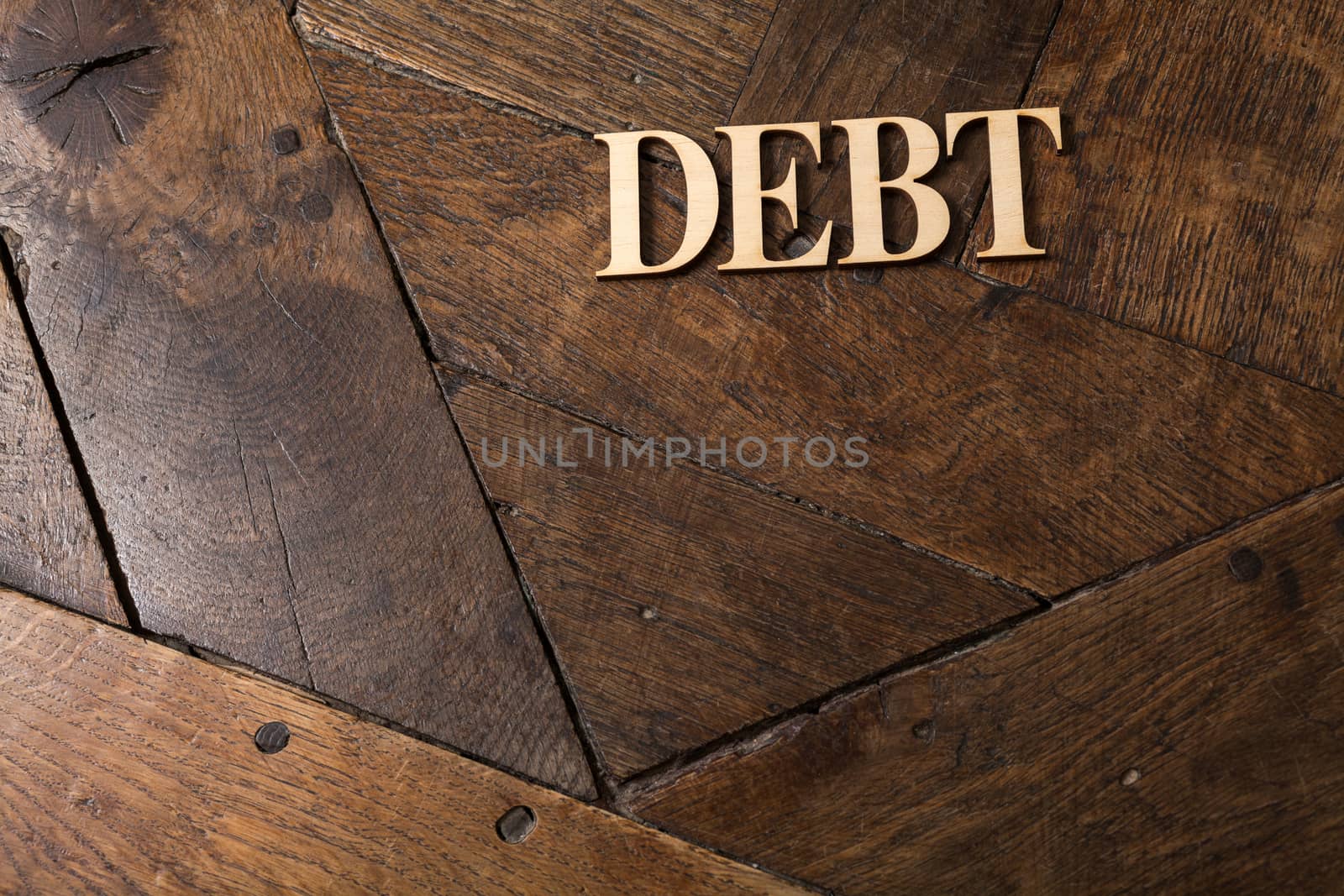 Wooden letters forming word DEBT written on old vintage wooden plates with space for your own text.