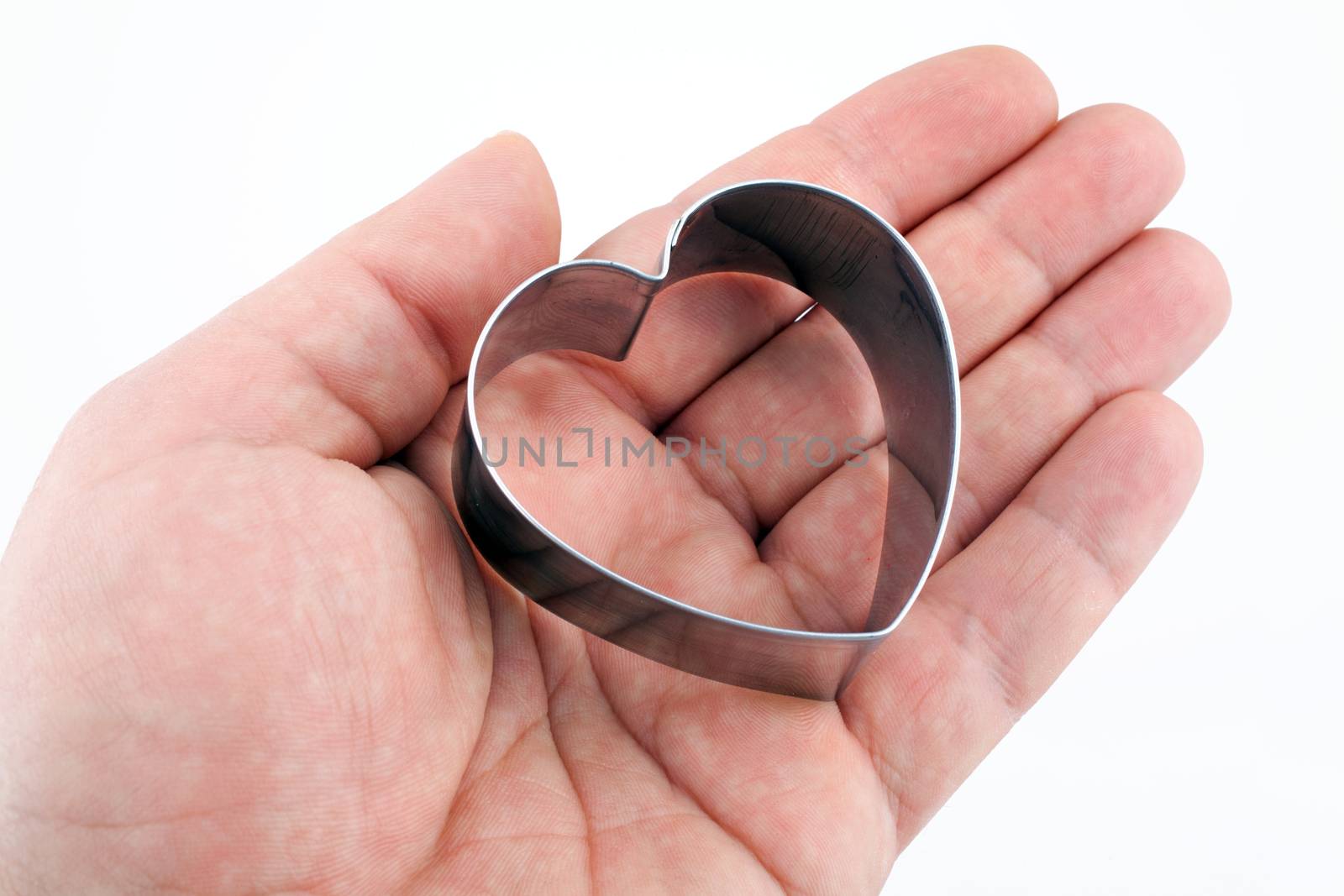 Male hand holding a metallic heart on white background