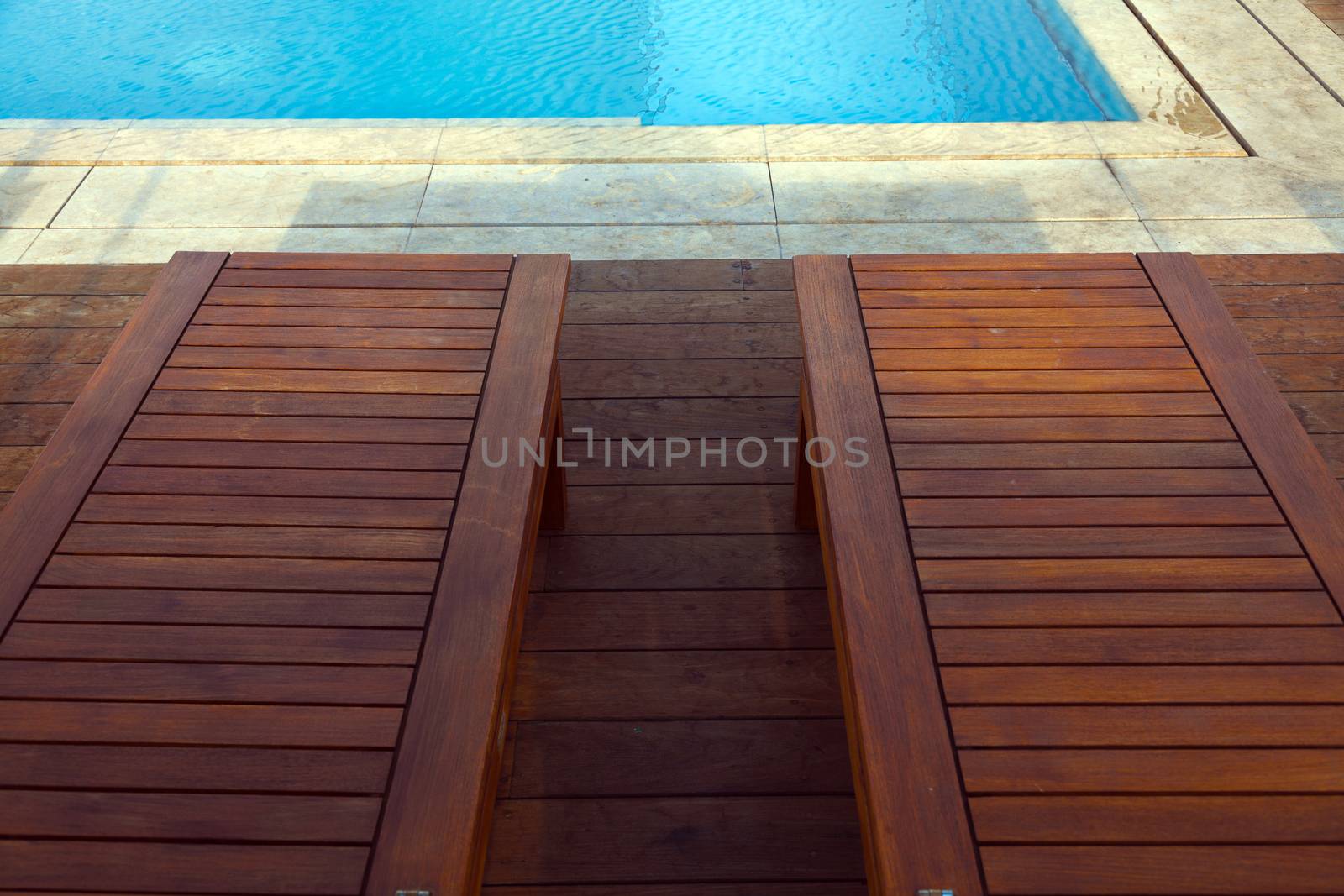 Wooden sunbeds next to a swimming pool