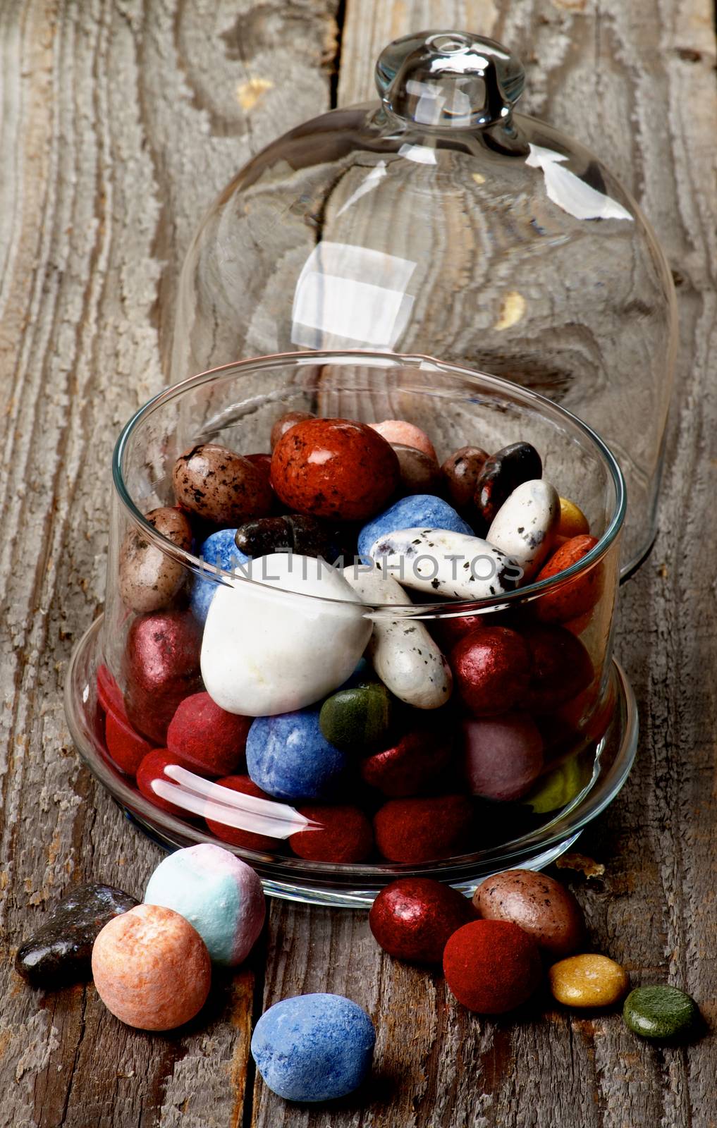 Various Colored Gum and Hard Candies in Glass Jar with Lid closeup on Rustic Wooden background