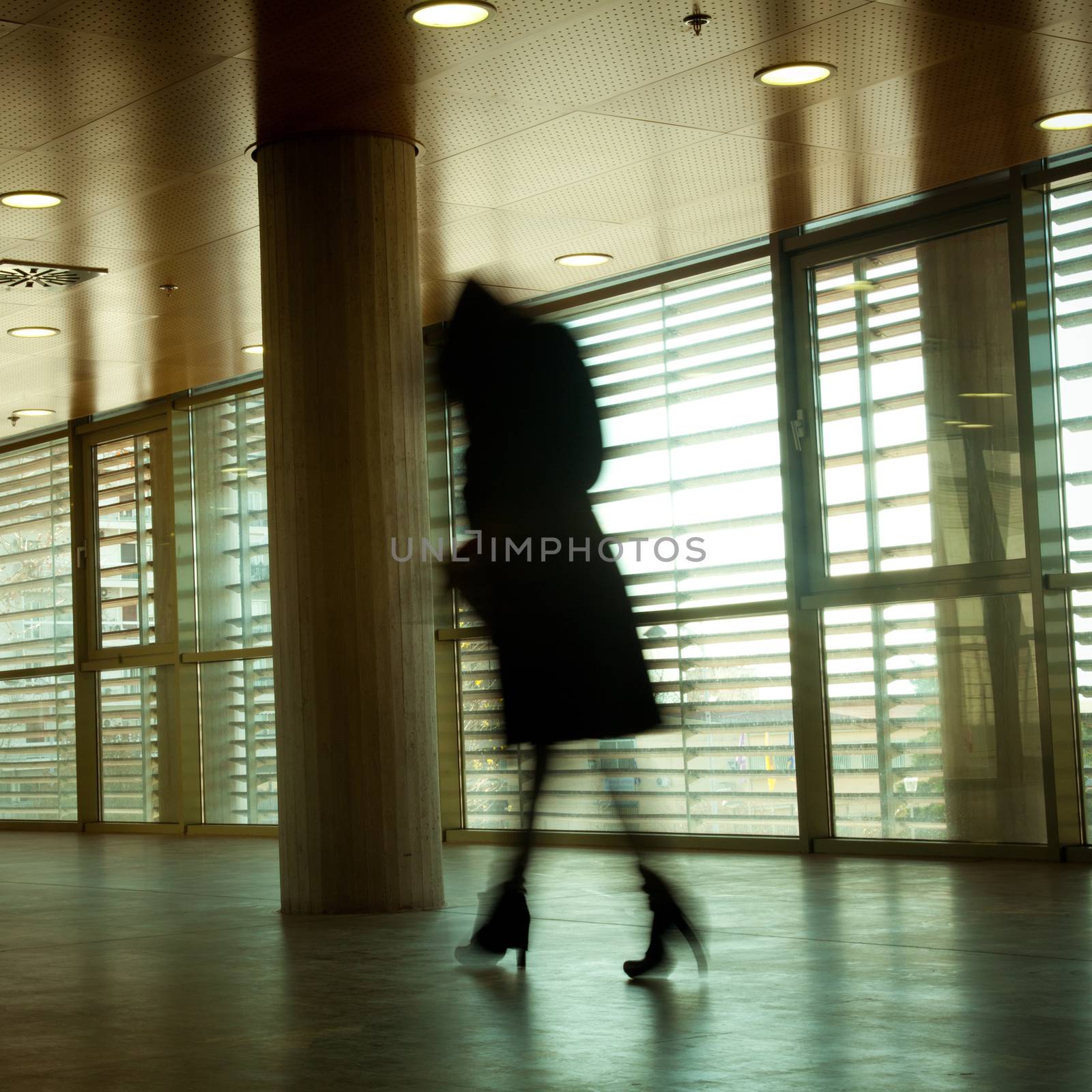 Intentional motion blurred image of a business people group walking in office lobby. All exposed faces are motion blurred.