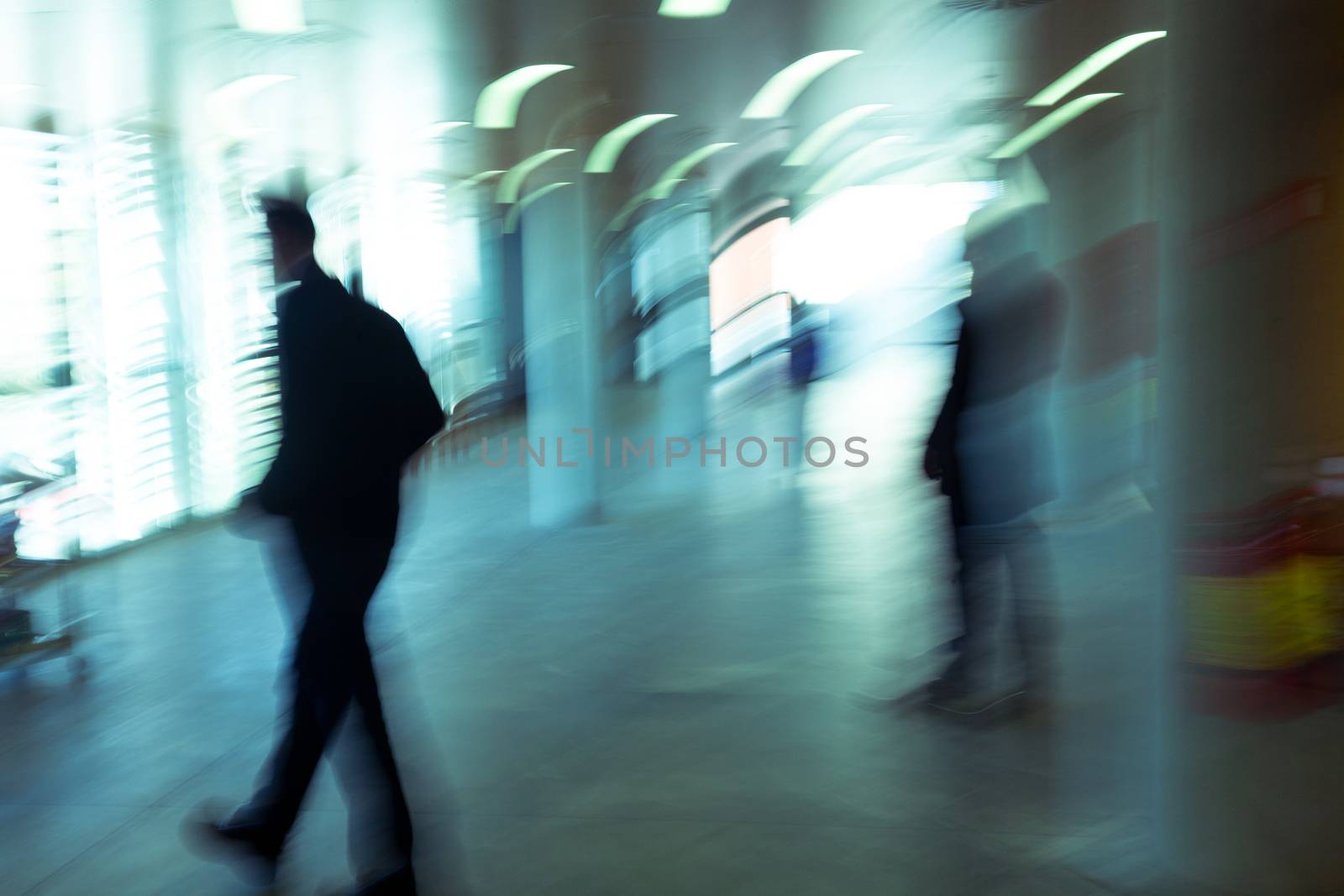 Intentional motion blurred image of a business people group walking in office lobby. All exposed faces are motion blurred.