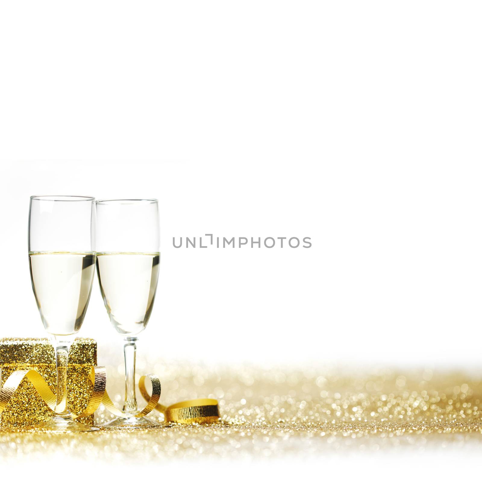 Champagne glasses and gift on glitters with white copy space