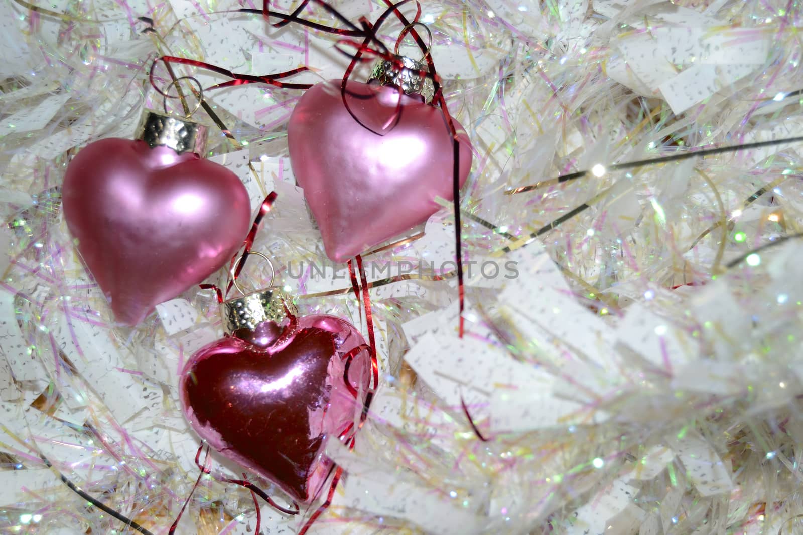 three pink hearts and white garland. Christmas balls with the shape of a heart