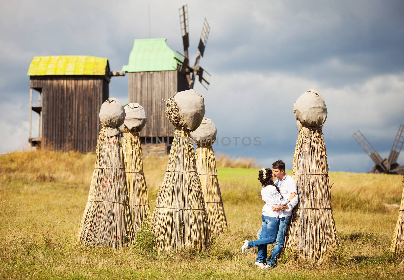 Couple kissing on field with bundles of straw by photobac