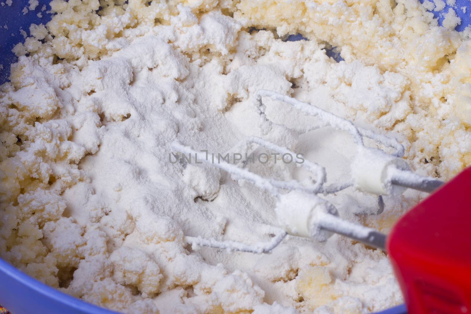 Mixer beat the dough in a blue bowl