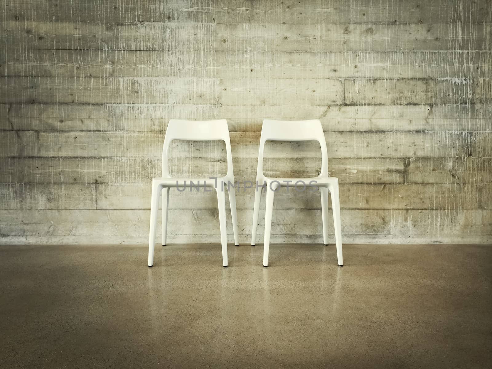 White chairs near concrete wall, modern industrial design.