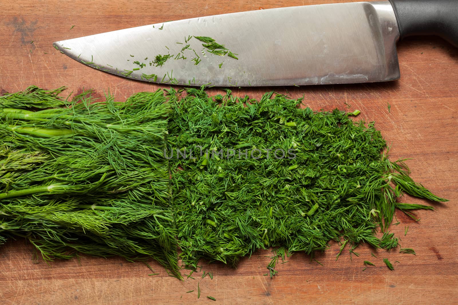 Fresh dill sprigs on wooden board cutting with knife